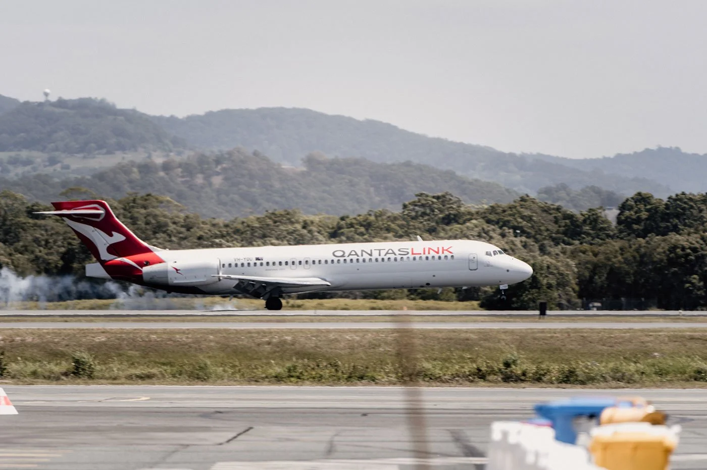A QantasLink airplane taking off from an airport runway.