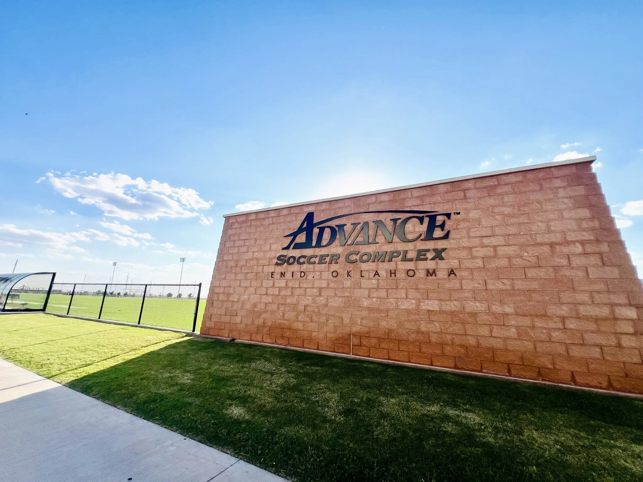 Sign for Advance Soccer Complex at Oklahoma stadium with blue sky and clouds in the background.