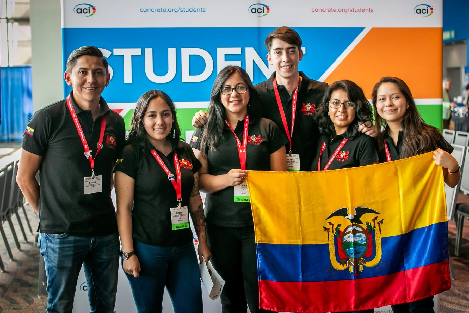 Grupo de jóvenes sosteniendo una bandera de Ecuador en un evento de estudiantes, con carteles del congreso y logotipos en el fondo.