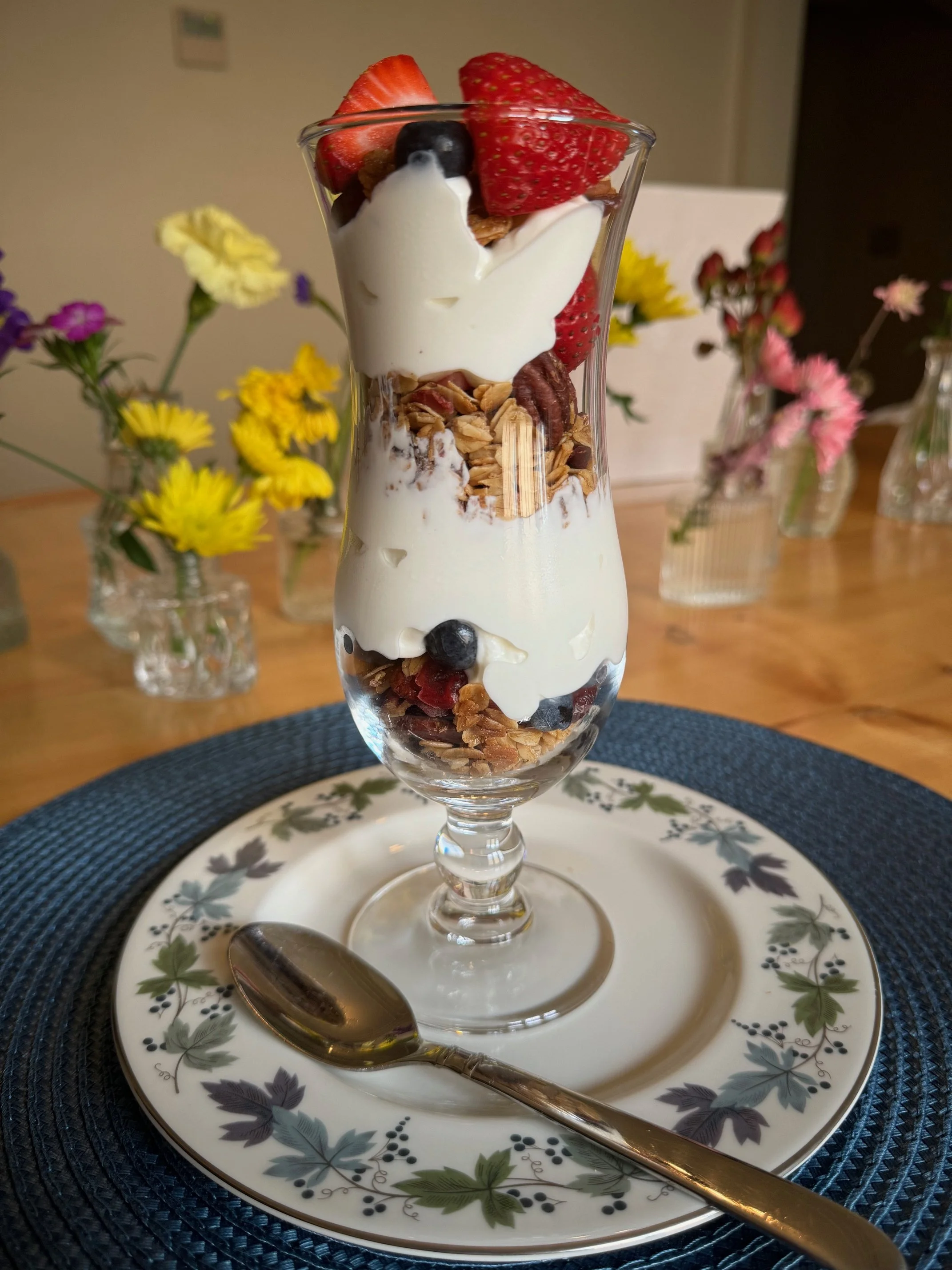 Beautiful fruit, granola and yogurt parfait with perfectly browned toast on fine china plate.