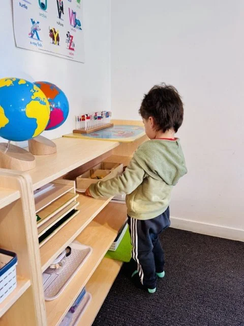 Child independently selecting Montessori-inspired learning resources, encouraging confidence, choice and self-directed learning.