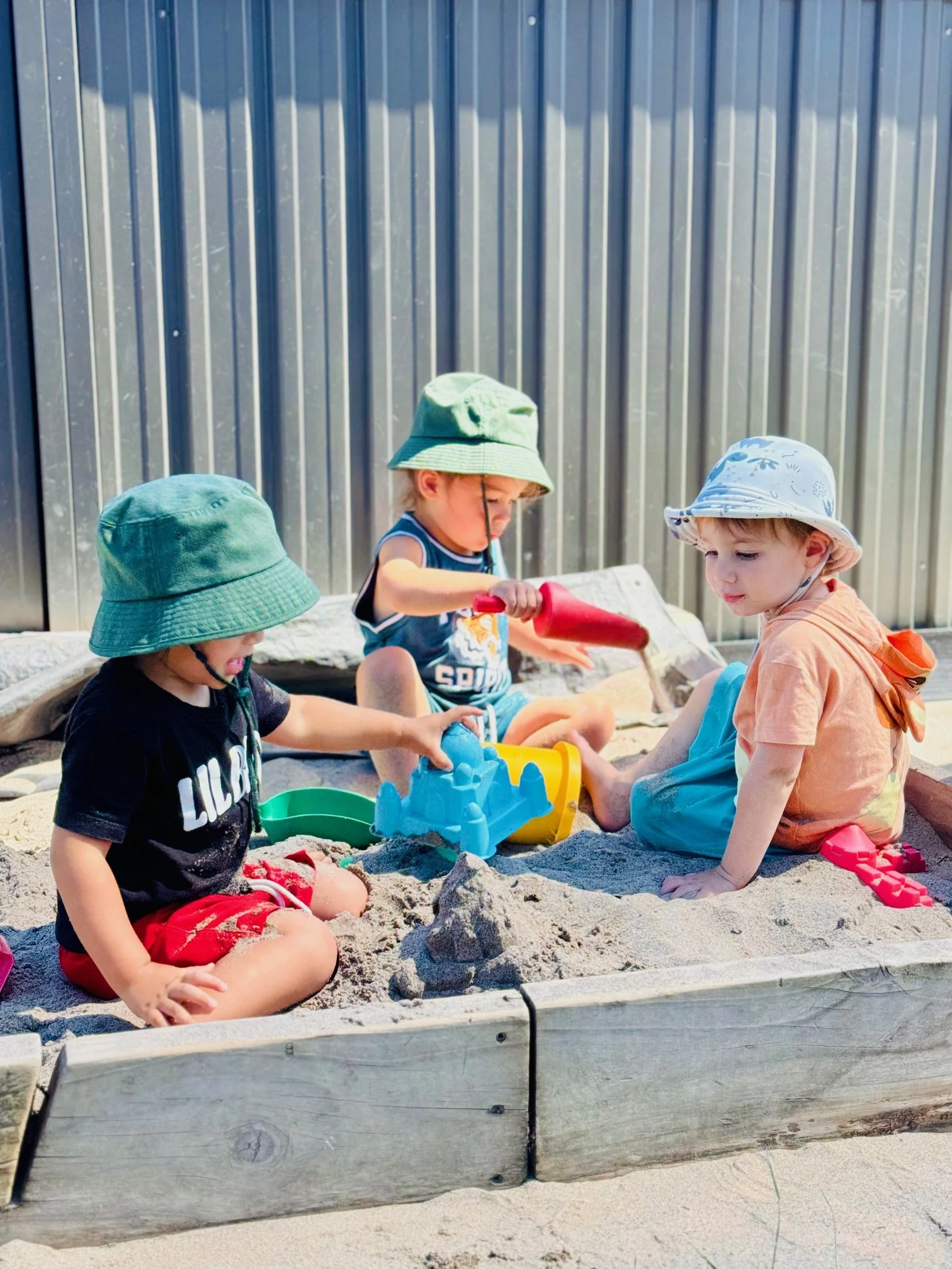 Children exploring the sandpit together, building creativity, collaboration, sensory awareness and fine motor skills through open-ended play.