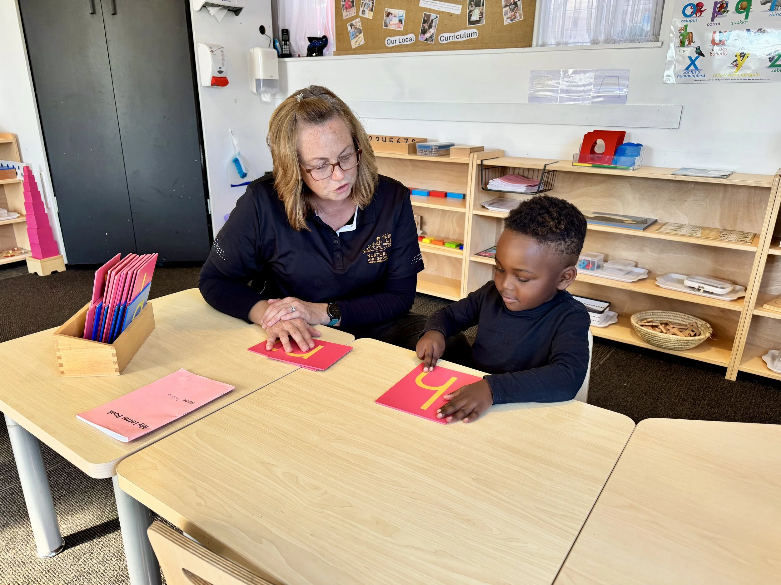 Teacher supporting early literacy through Montessori-inspired learning experiences, building confidence and school readiness..