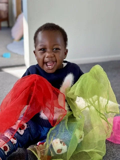 Child exploring colourful sensory materials, encouraging creativity, curiosity and confidence through child-led play.