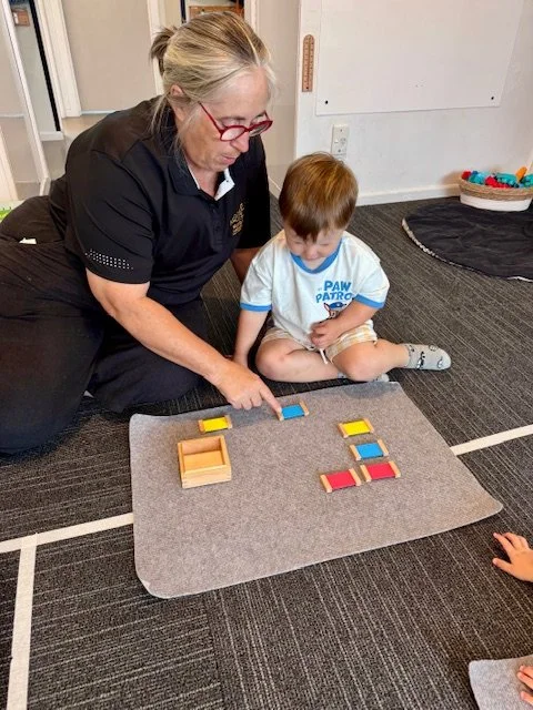 Teacher supporting hands-on learning through construction play, developing confidence, concentration and problem-solving.