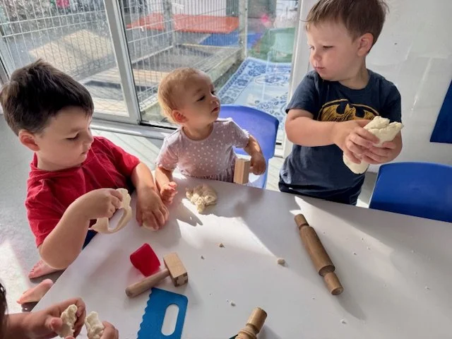 Children developing hand strength and fine motor control through playdough experiences, supporting early writing and school readiness.