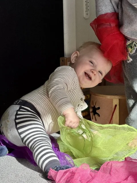 Infant exploring sensory materials through play, supporting curiosity, confidence and early development in a nurturing environment.