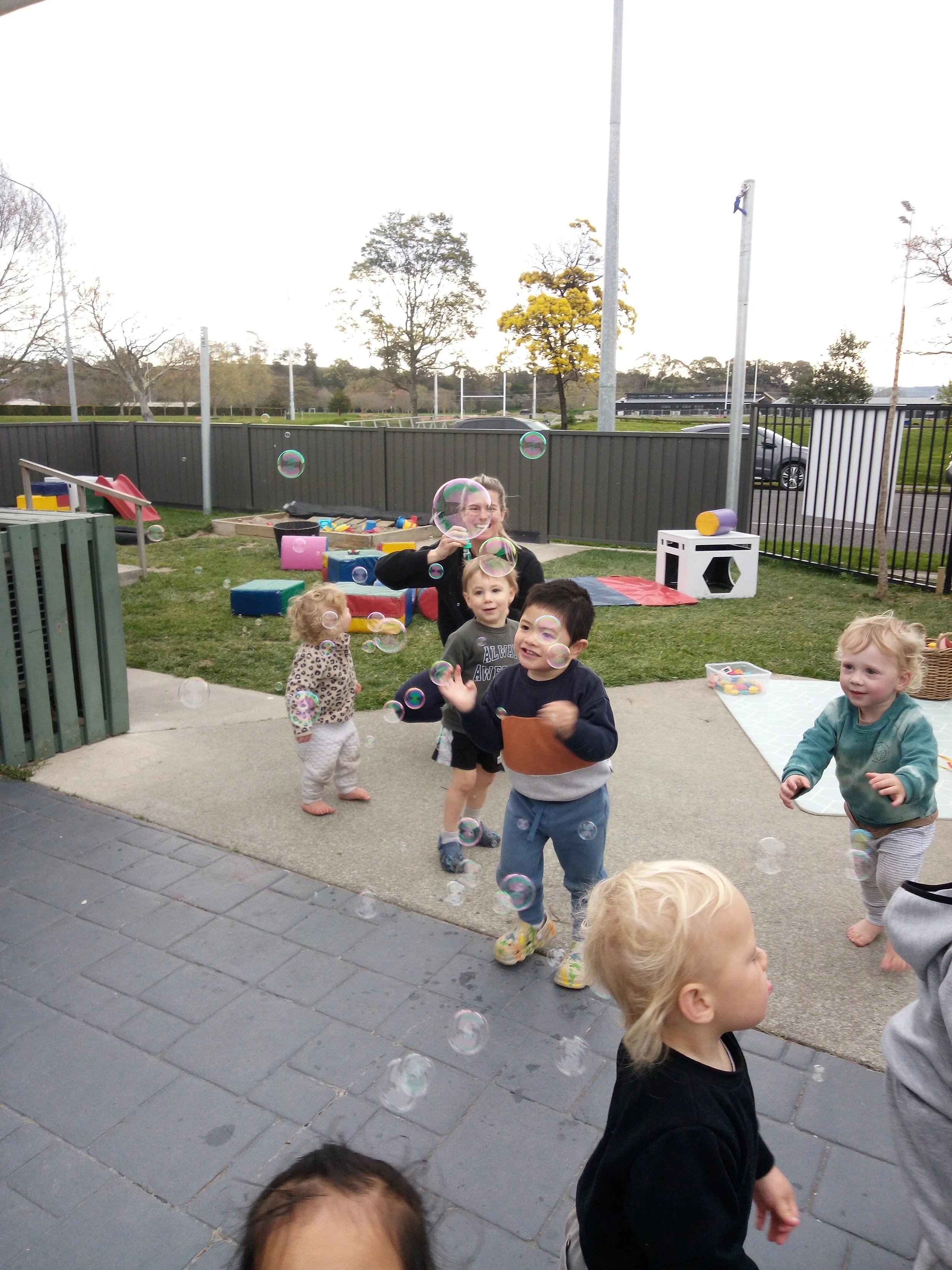 Children exploring outdoor play together, developing confidence, creativity, communication and gross motor skills through open-ended learning experiences.