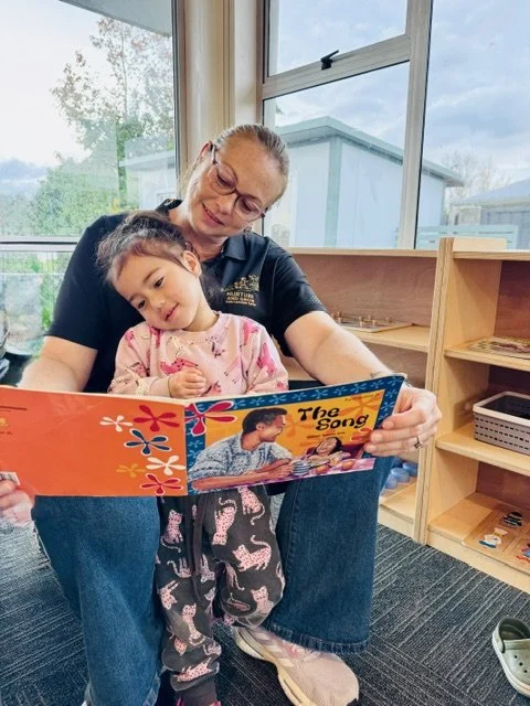 Teacher sharing a story with a child, fostering early literacy, language development and a love of books through meaningful one-on-one interactions.