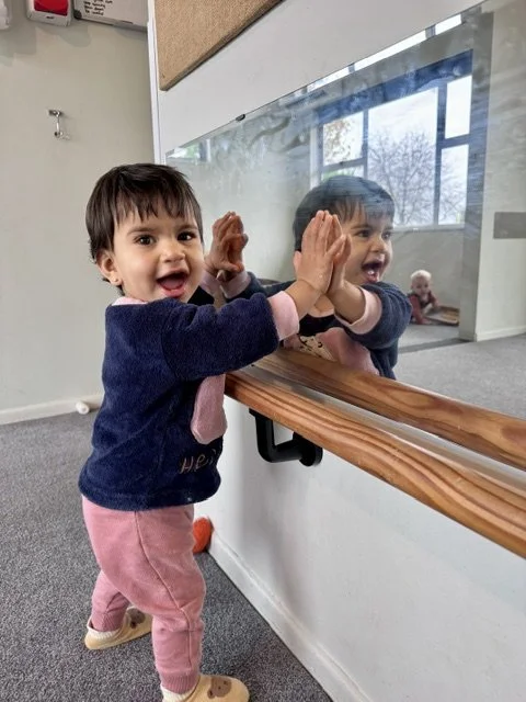 Toddler exploring their reflection, supporting self-awareness, confidence and curiosity through independent exploration.