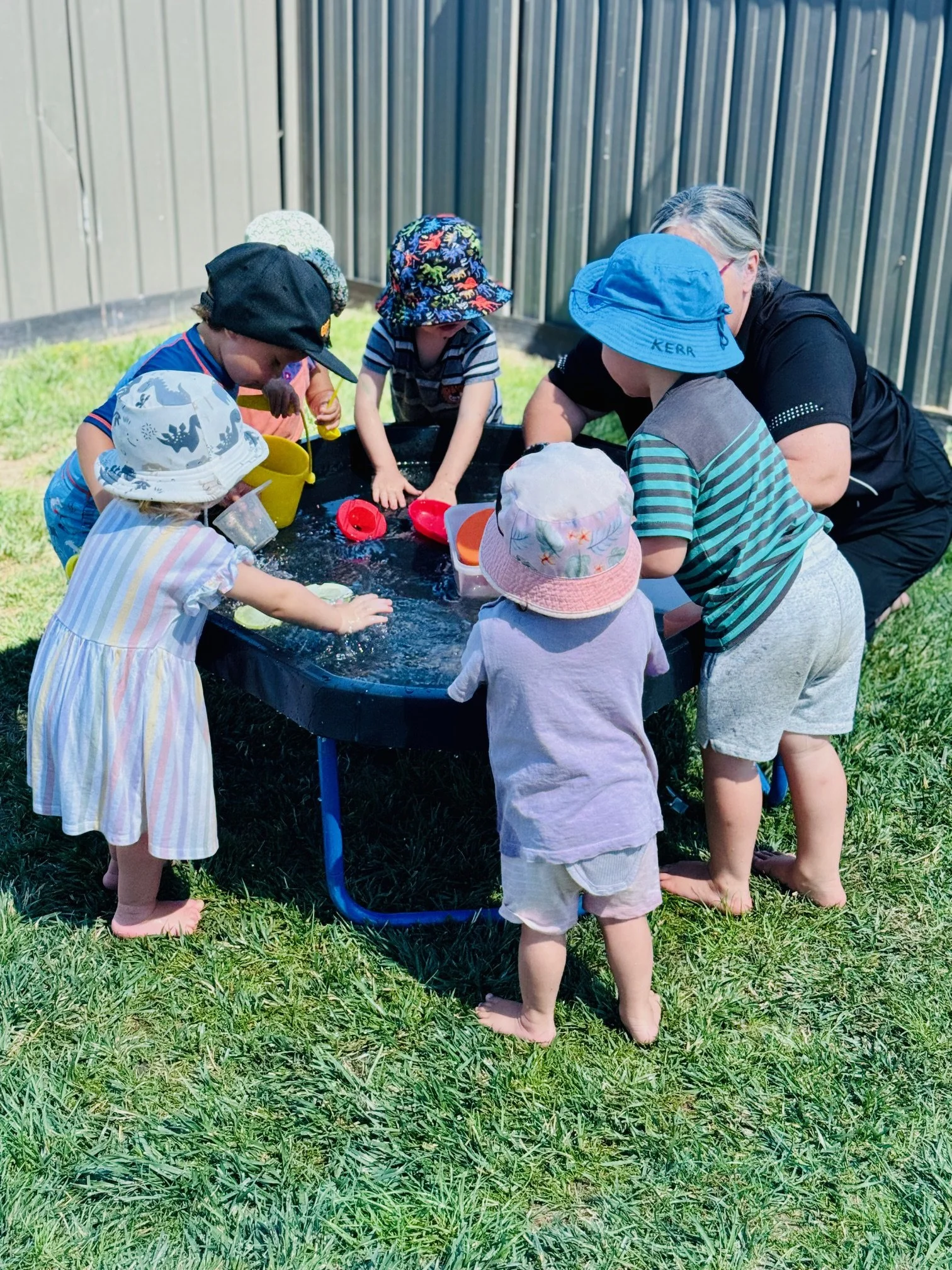 Children exploring water play together, developing curiosity, cooperation, problem-solving and sensory learning through hands-on outdoor experiences.