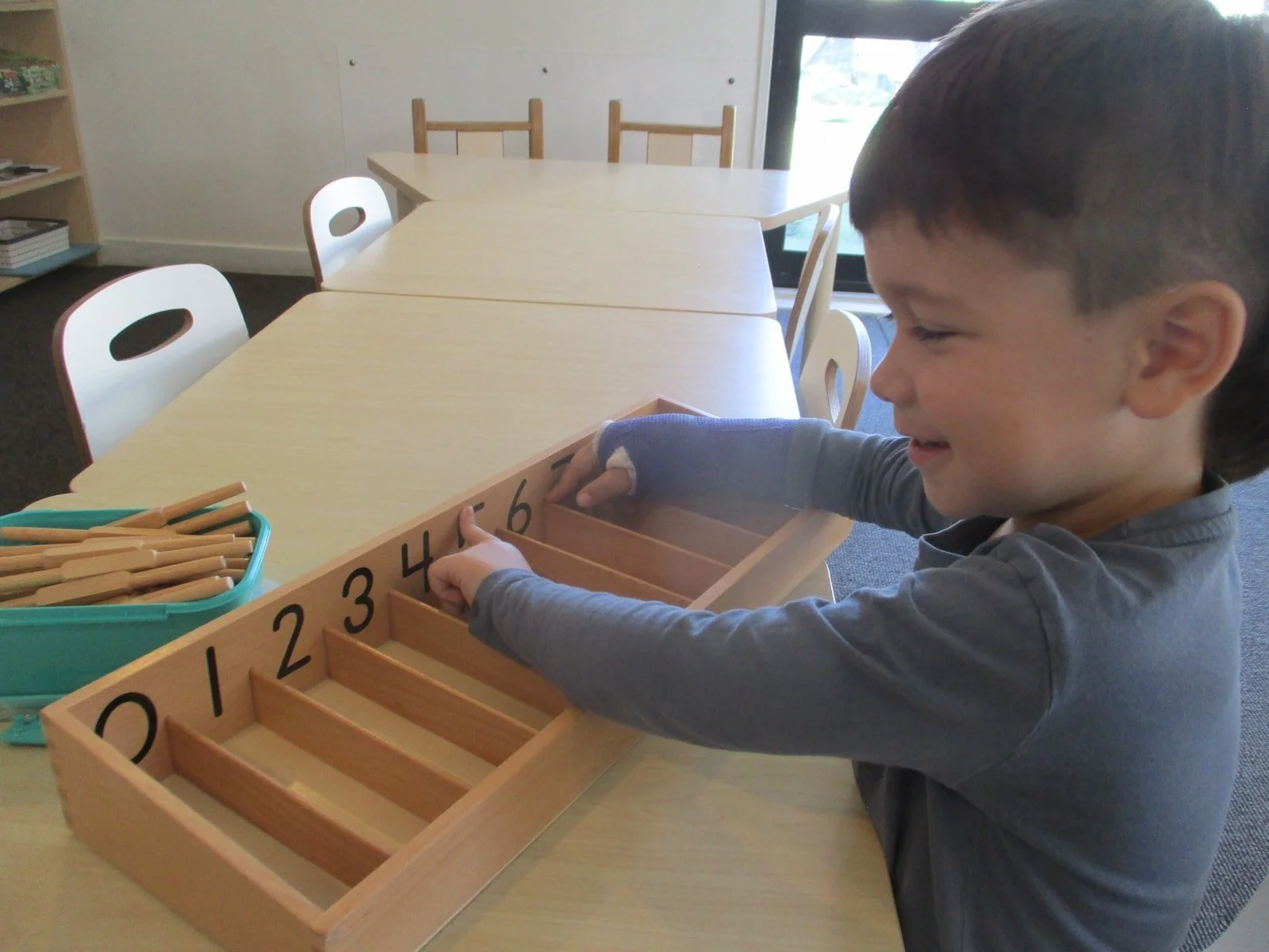 Child using Montessori-inspired numeracy materials to develop number recognition, concentration and problem-solving skills through hands-on learning.