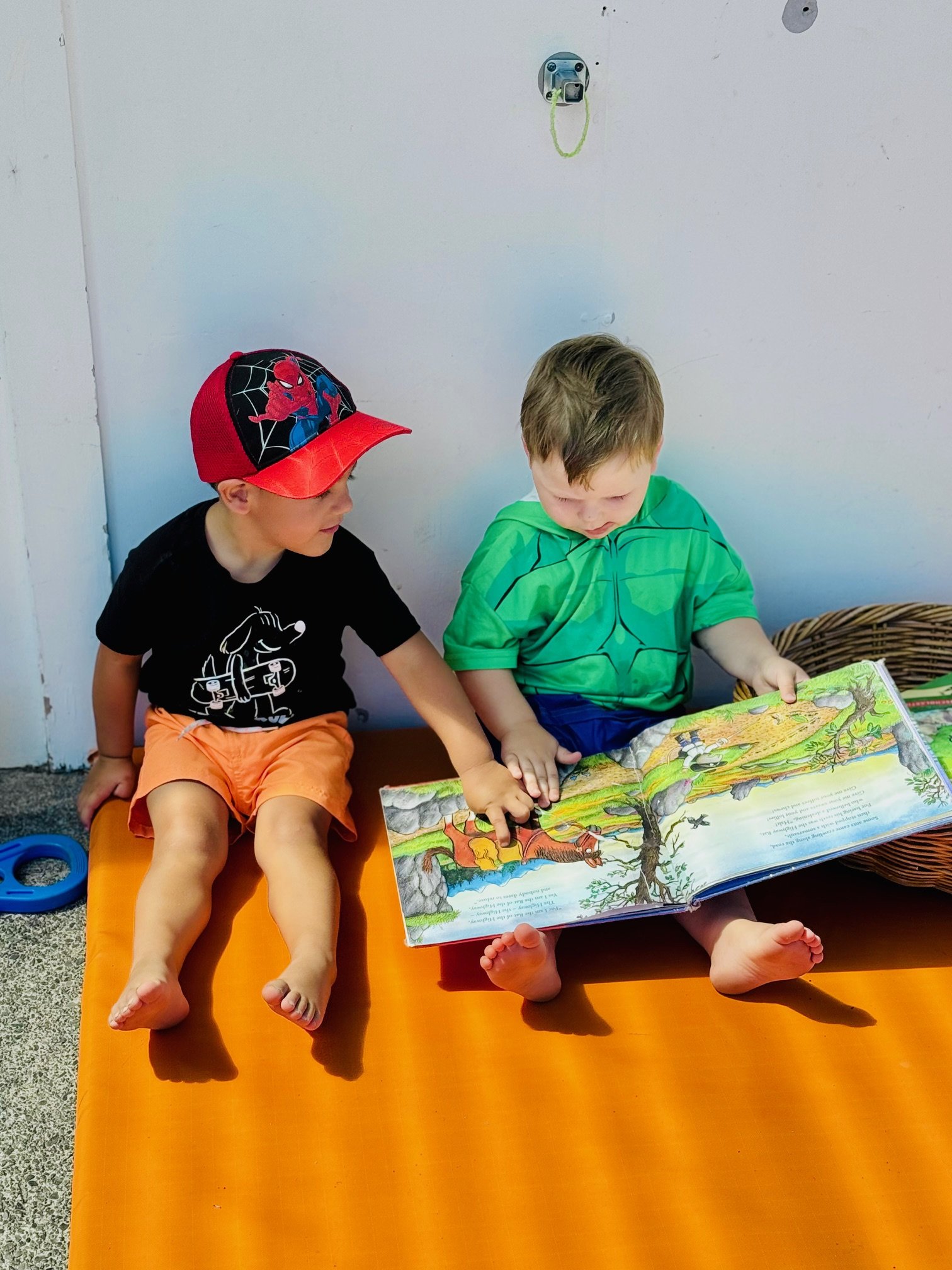 Children enjoying books together outdoors, supporting early literacy, communication and a lifelong love of reading.