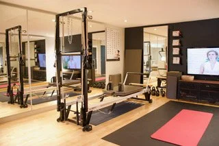 Gym room with fitness equipment, a treadmill, and a pink yoga mat on the floor.