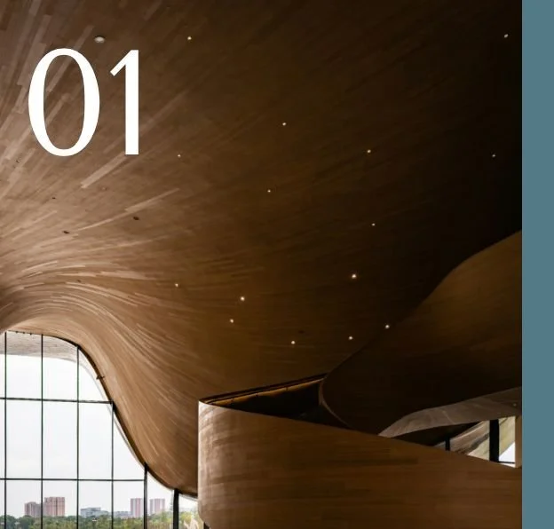 Interior view of a modern building with a curved wooden ceiling and large glass windows, showing a city skyline outside with a number 01 in top corner.