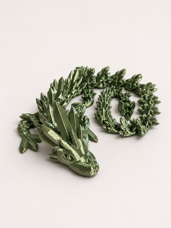 A metallic green mechanical dragon toy with pointed scales and a long, winding tail on a plain white surface.