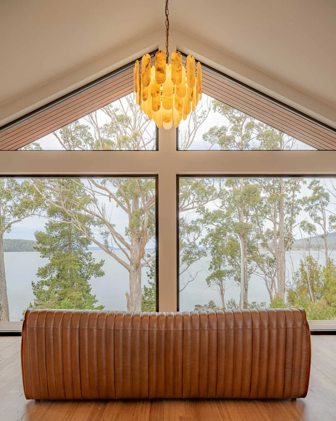 Interior view of a room with large floor-to-ceiling windows showcasing a chandelier made of amber-colored glass hanging from the ceiling.