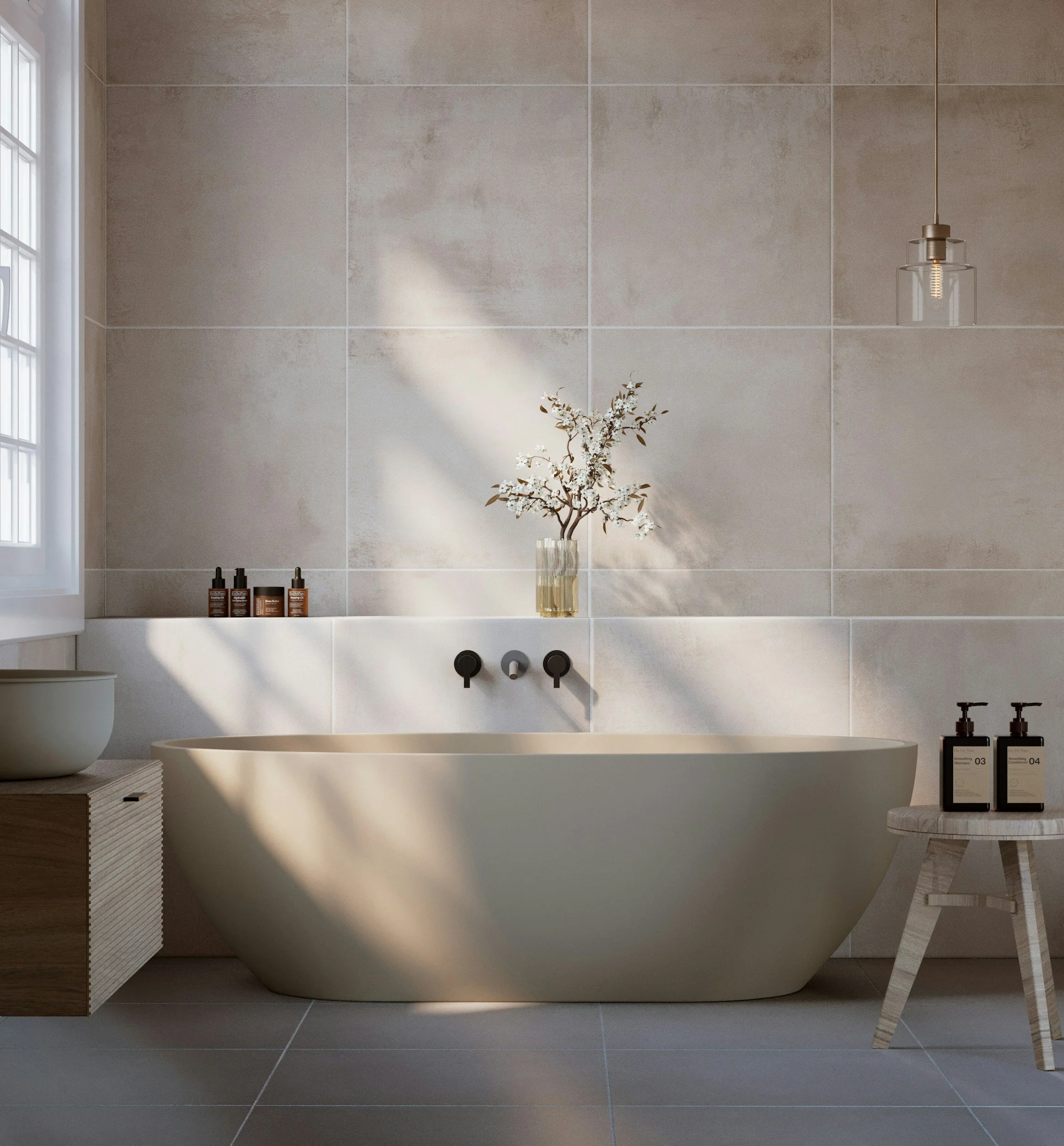 Modern bathroom with a white bathtub, beige tiled wall, wooden cabinet with three bottles, a potted plant, a small marble side table with two bottles, and a pendant light with a clear glass shade hanging from the ceiling.