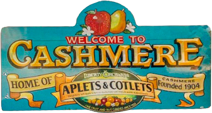 Welcome sign for Cashmere featuring apples and pears, with a banner for Aplets & Cotlets cakes and candies, established in 1904.