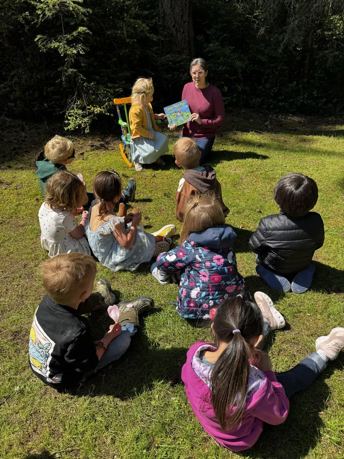 Teacher reading a story to preschool children during outdoor circle time at Gig Harbor Cooperative Preschool.