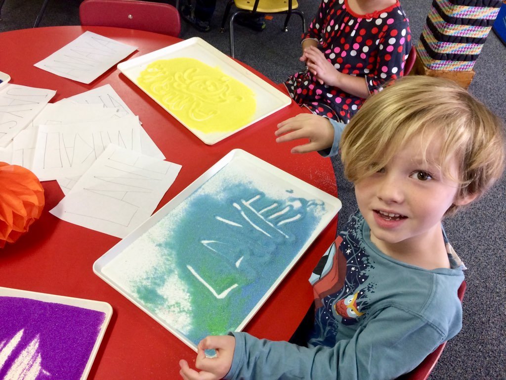 Child exploring early literacy and writing skills through hands-on sensory play.