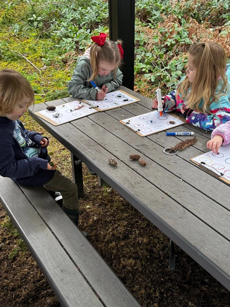Children observing and recording nature during outdoor exploration.