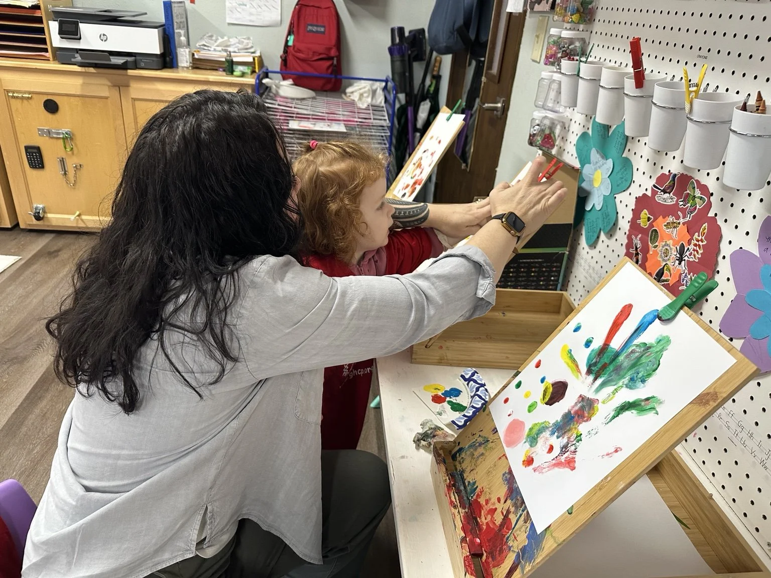 Teacher and child creating art together during a classroom activity.