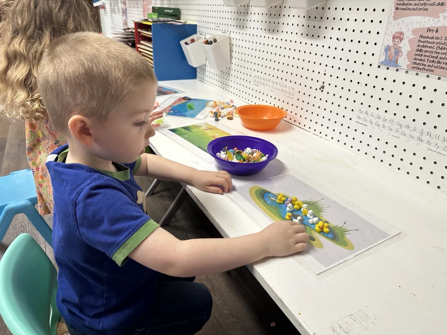 Child strengthening fine motor skills through a hands-on classroom activity.