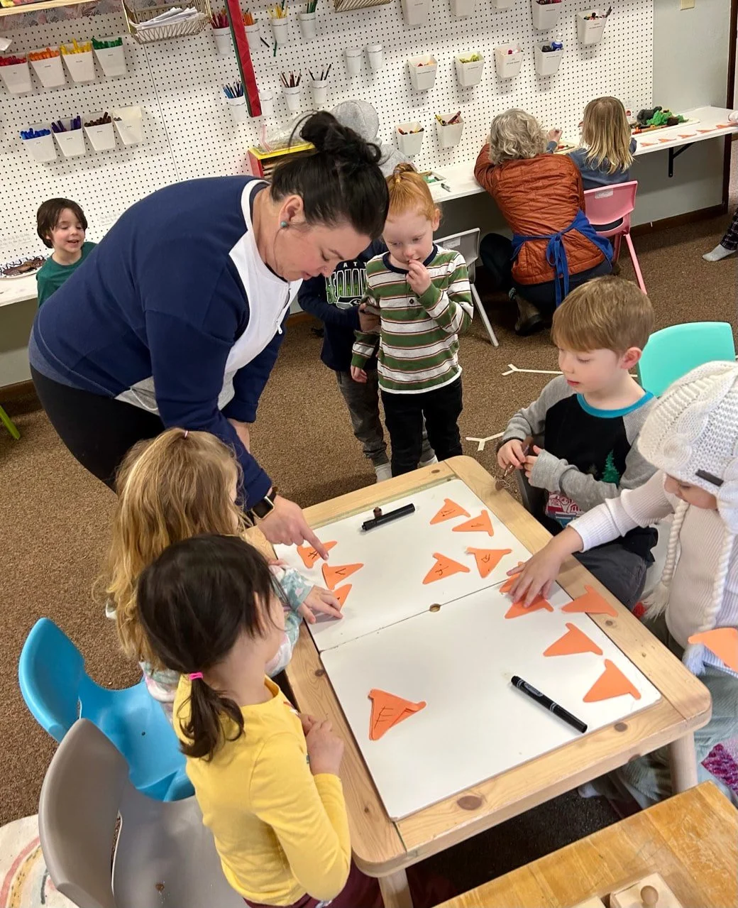 Children learning about shapes and letters through a hands-on classroom activity.