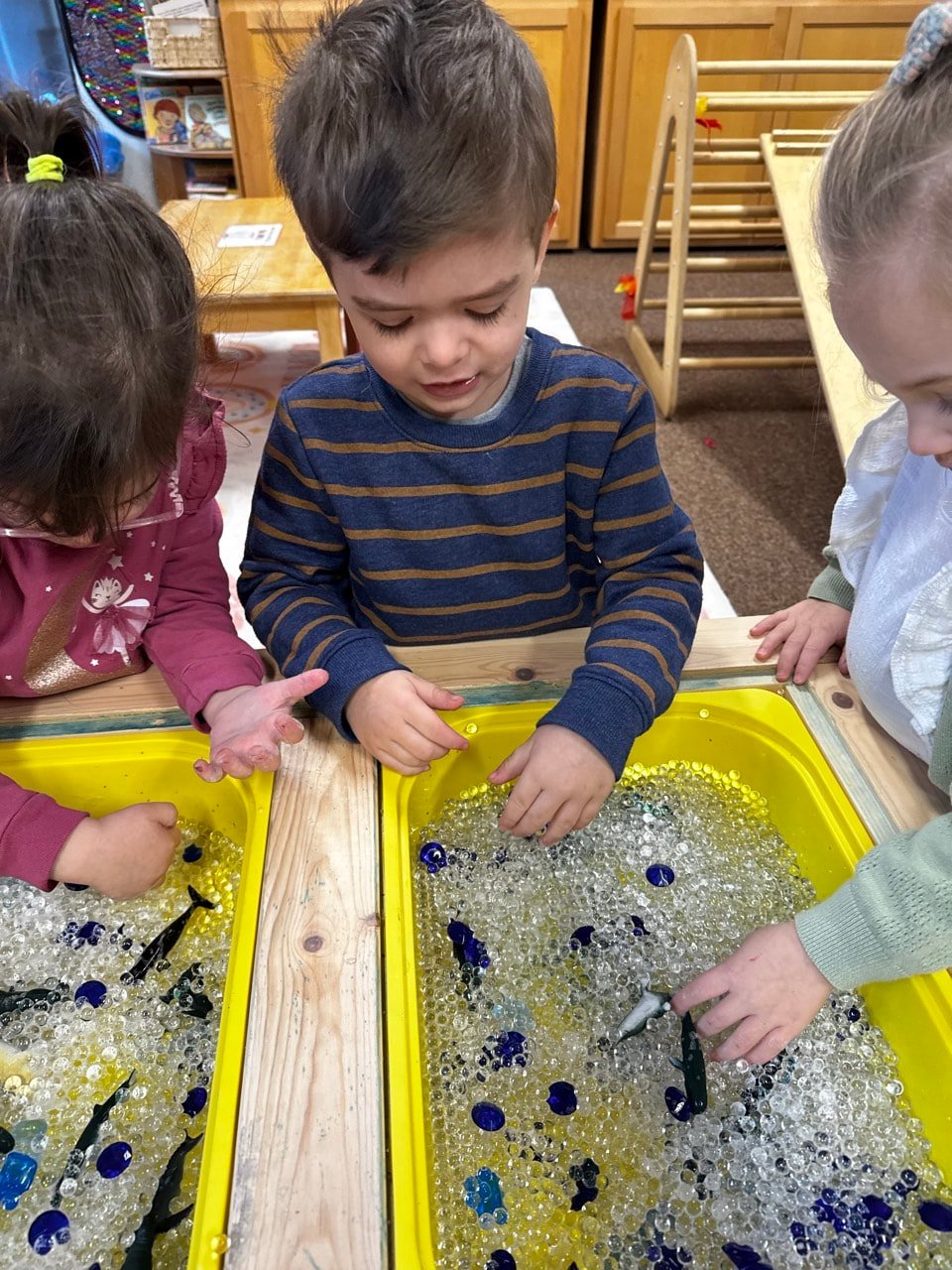 Children building fine motor skills through a fishing-themed sensory activity.