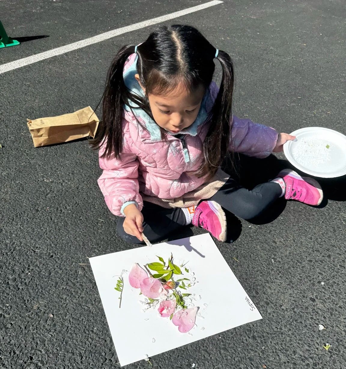 Child using flowers to create nature-inspired artwork.