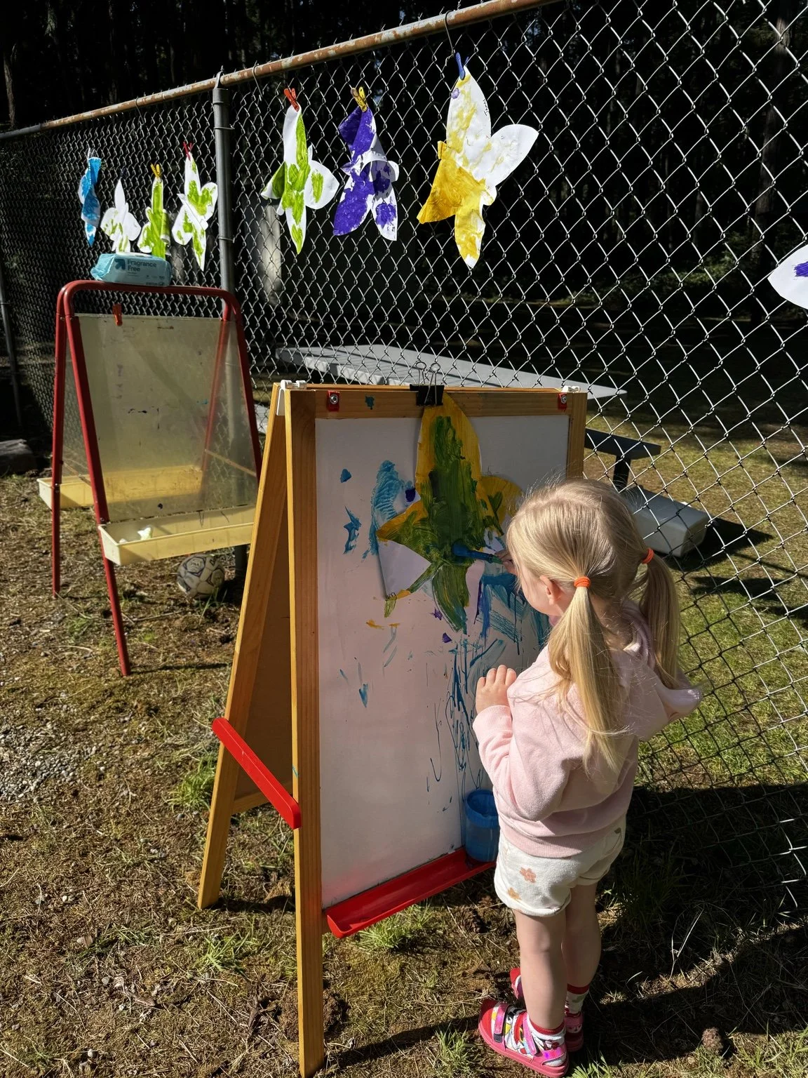 Child expressing creativity through outdoor art and painting.