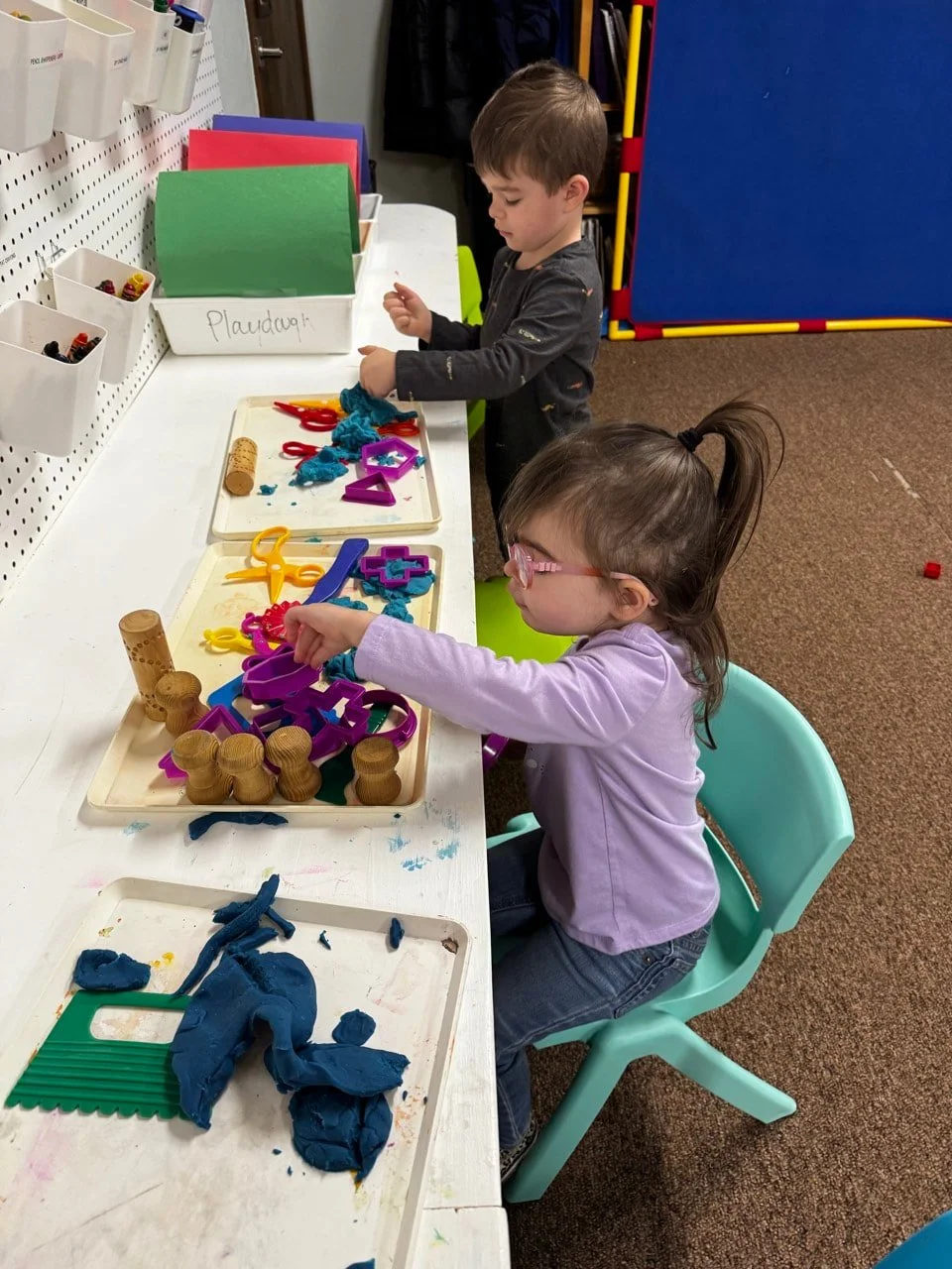 Children strengthening fine motor skills through playdough exploration.