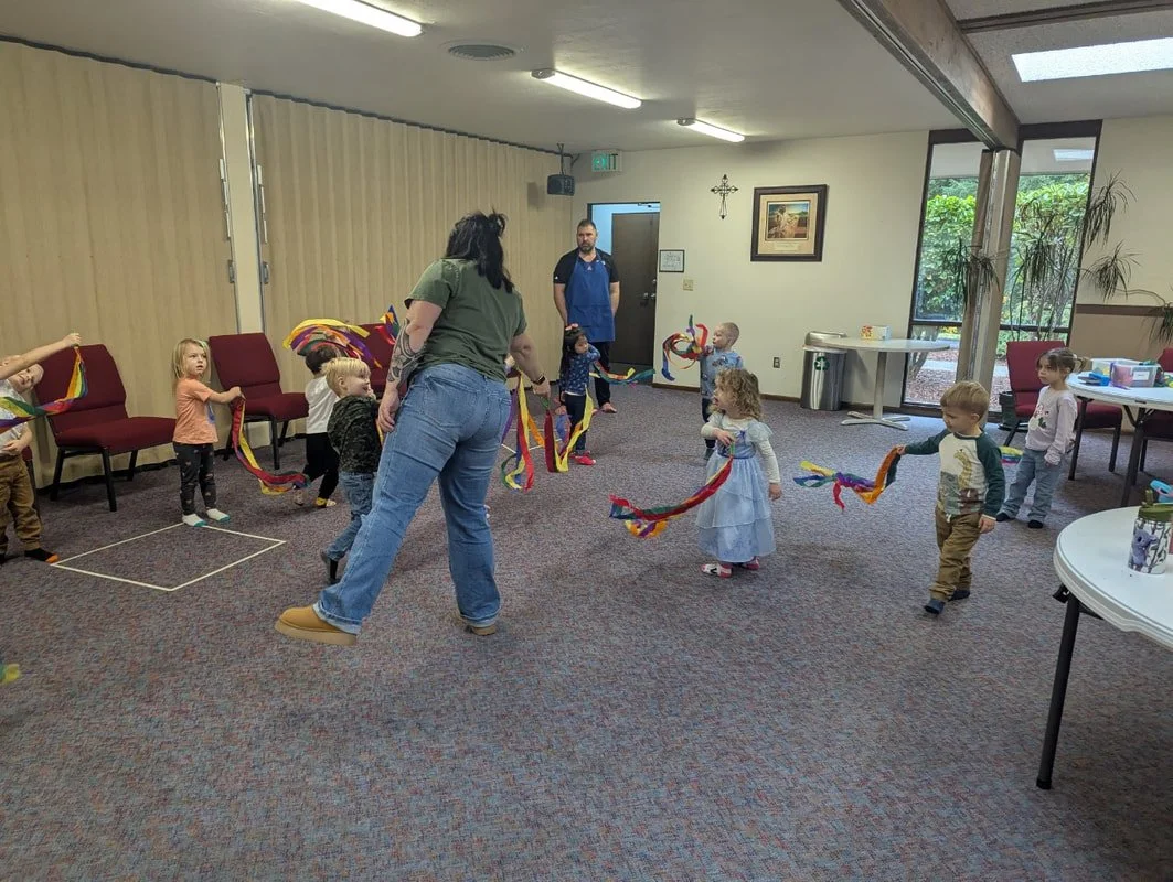 Children, teacher, and families enjoying music and movement together.