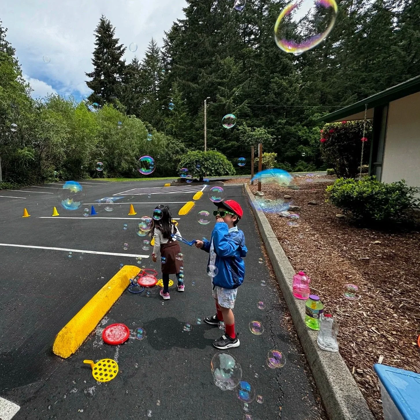 Children developing gross motor skills through outdoor bubble play.