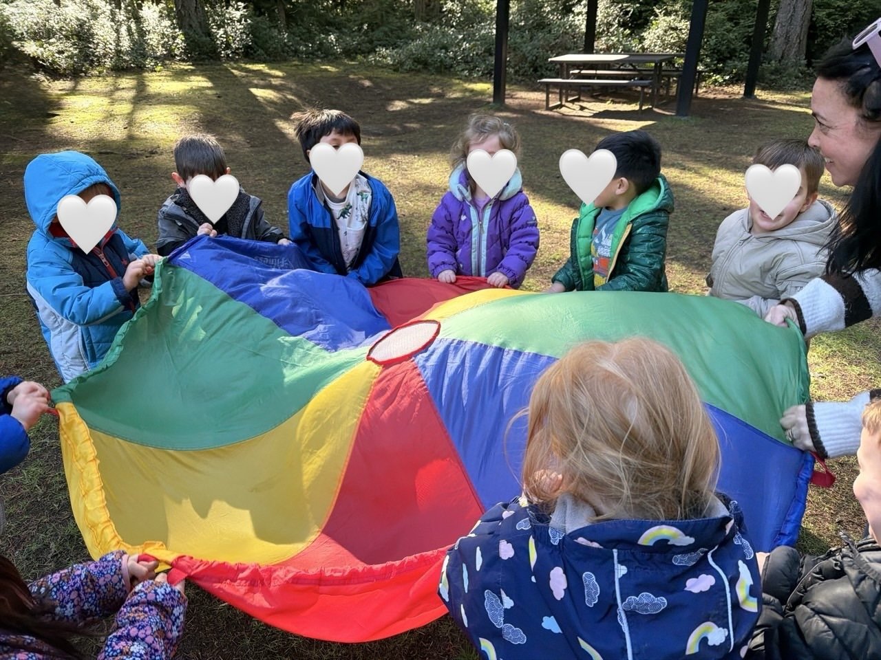 Children enjoying cooperative parachute play outdoors.