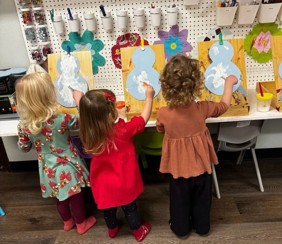 Preschool children painting holiday ornaments during creative art time.