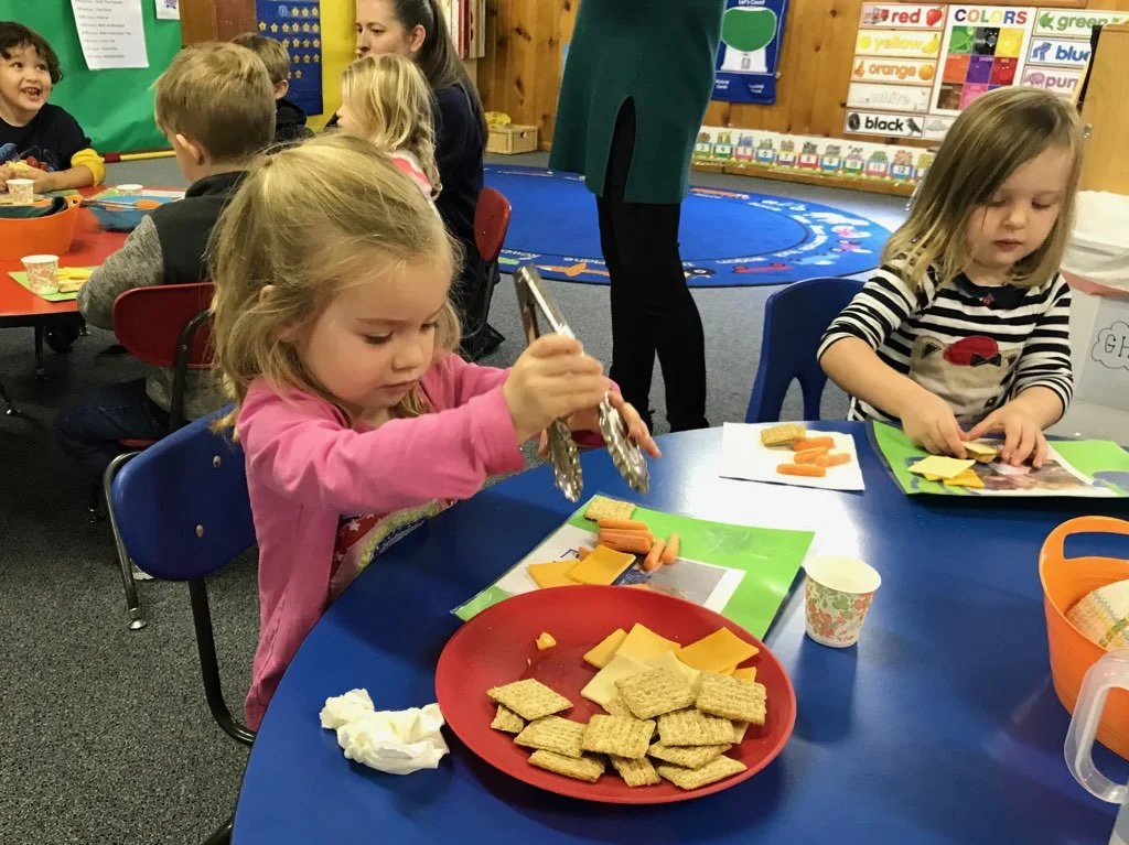 Children building independence by preparing a healthy classroom snack.
