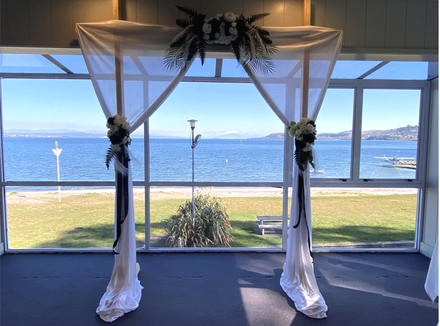 Wedding arch decorated with white flowers and green foliage, overlooking Lake Taupo
