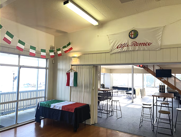 Taupo Yacht Club decorated with Italian flags and Alfa Romeo banners, featuring a table with an Italian flag-colored tablecloth, bars, and seating areas. Food by Cella Catering Co.