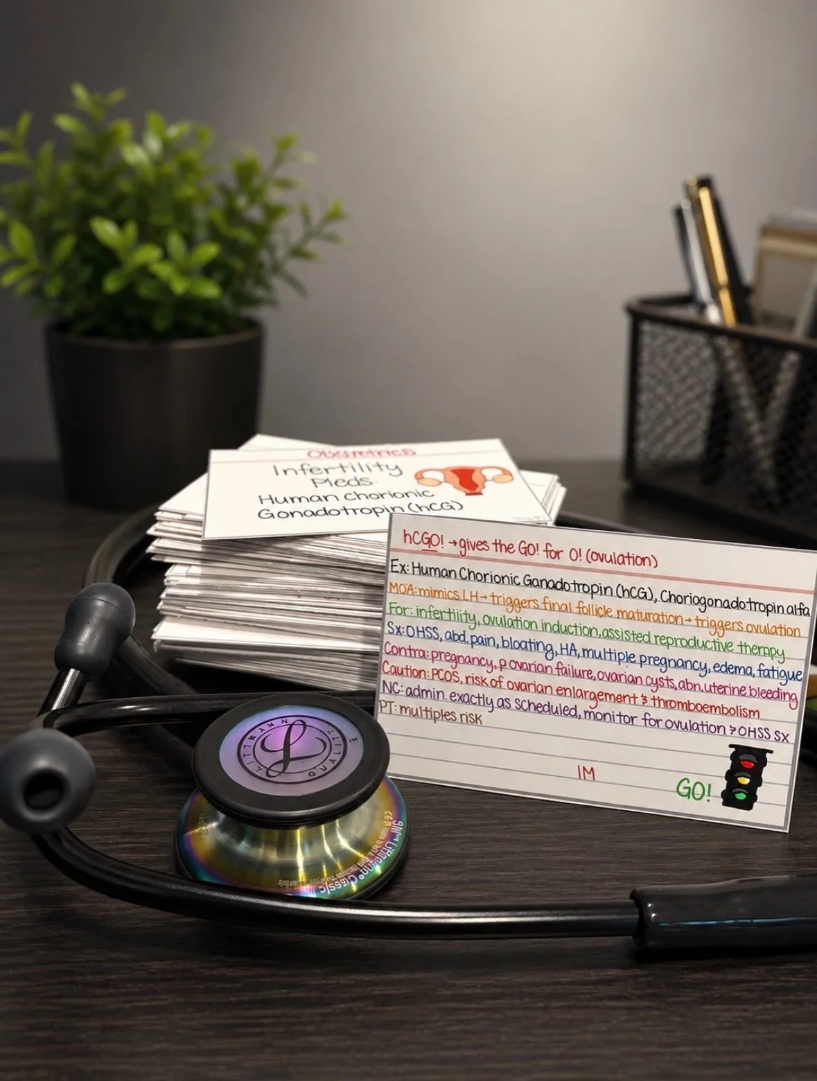 Medical table with a stethoscope, a stack of notecards about infertility and chorionic gonadotropin, and a background with a plant and a pen holder.
