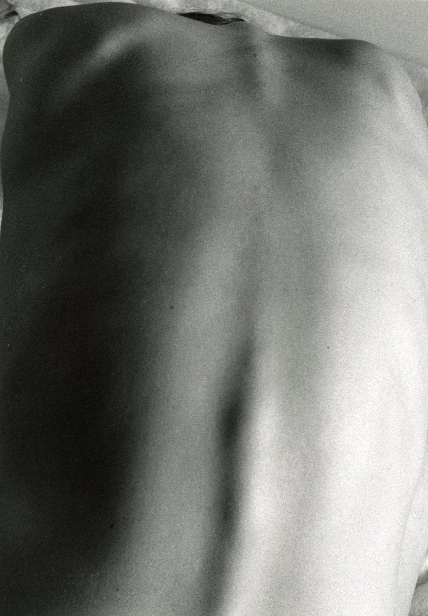Close-up of a person's back, showing their shoulder and spine in black and white.