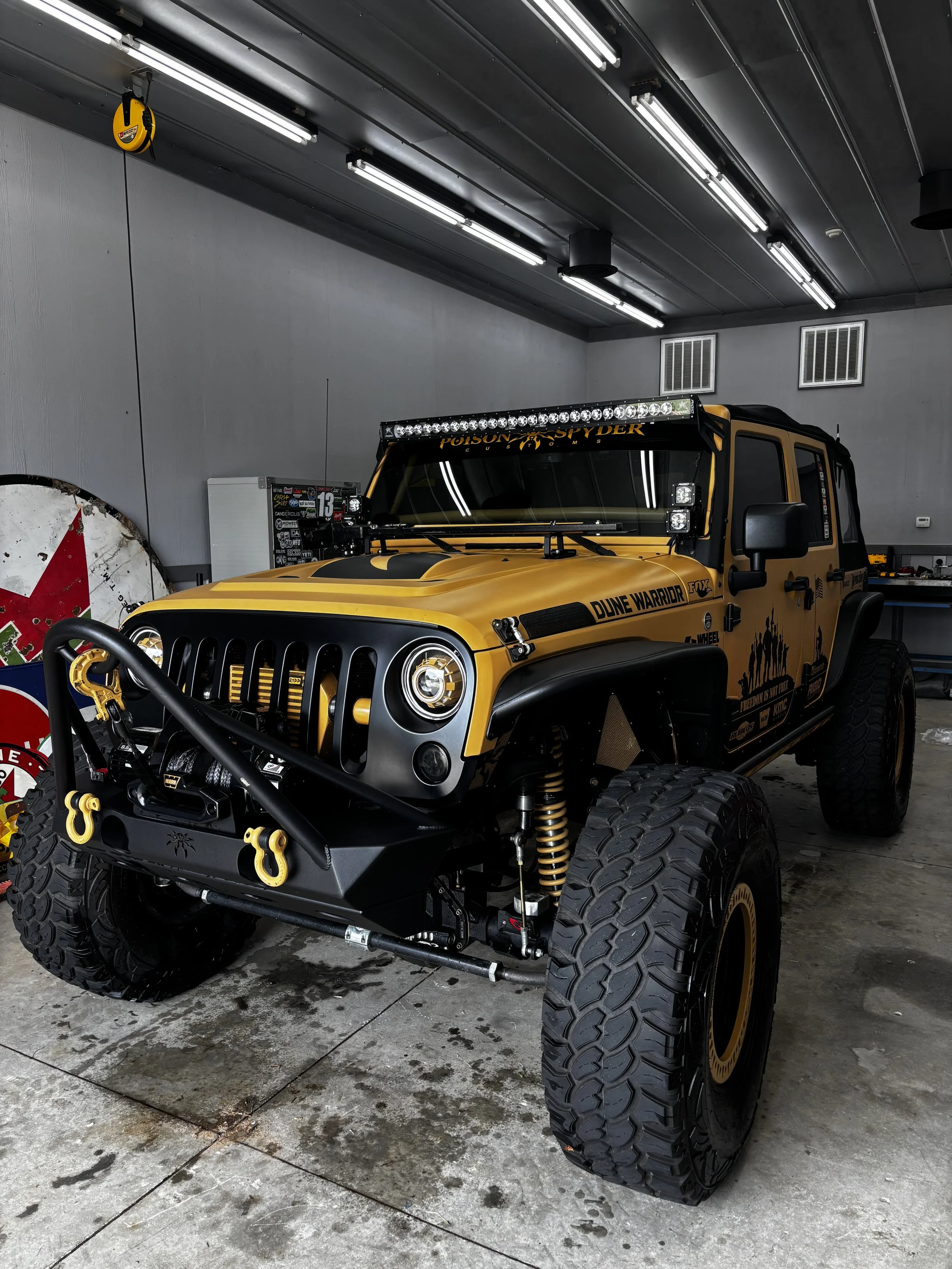 Yellow off-road vehicle with large tires and custom equipment inside a garage.