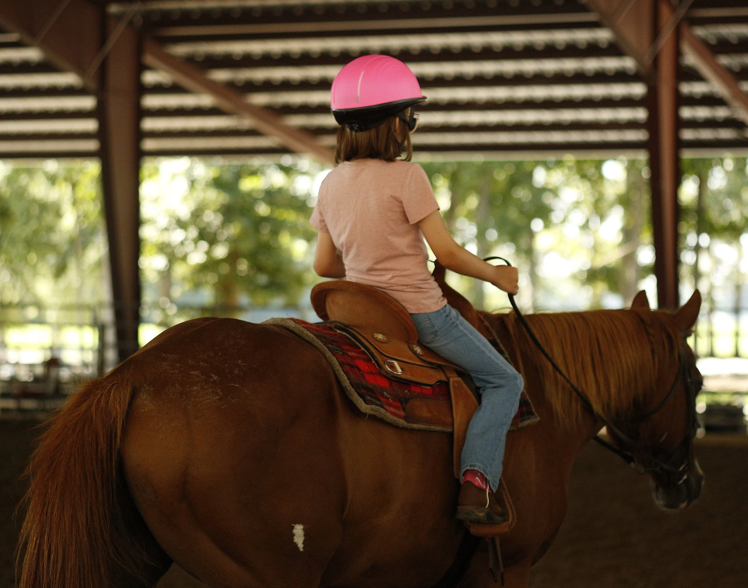A girl riding a horse away from the camera