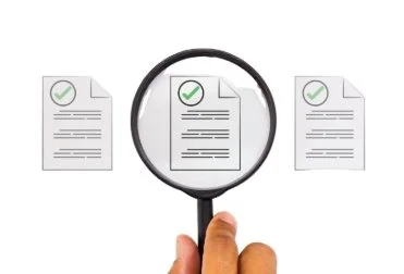 Person holding a magnifying glass over a document among three documents, all with green check marks.