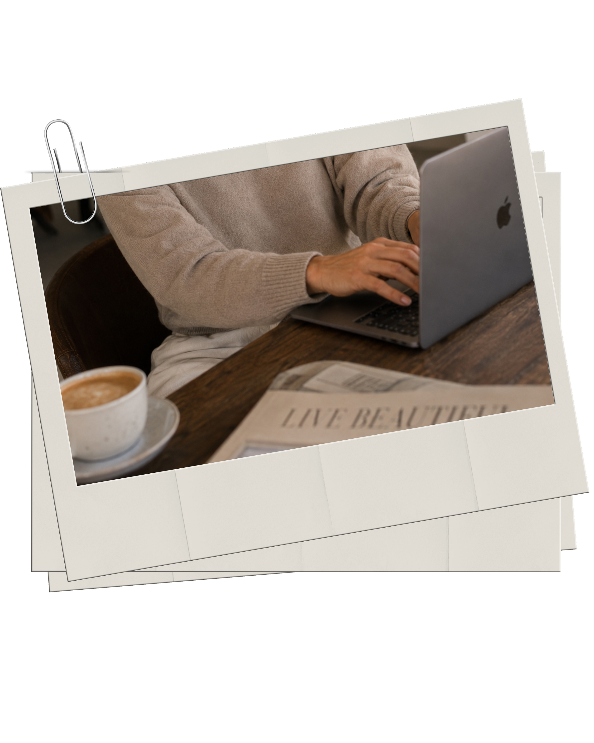 Haus of Whit Brand Photoshoot 2026. Whitney Radacina wearing a beige sweater sitting at a wooden table, typing on a laptop with an Apple logo, beside a cup of coffee and newspaper, with a black background.
