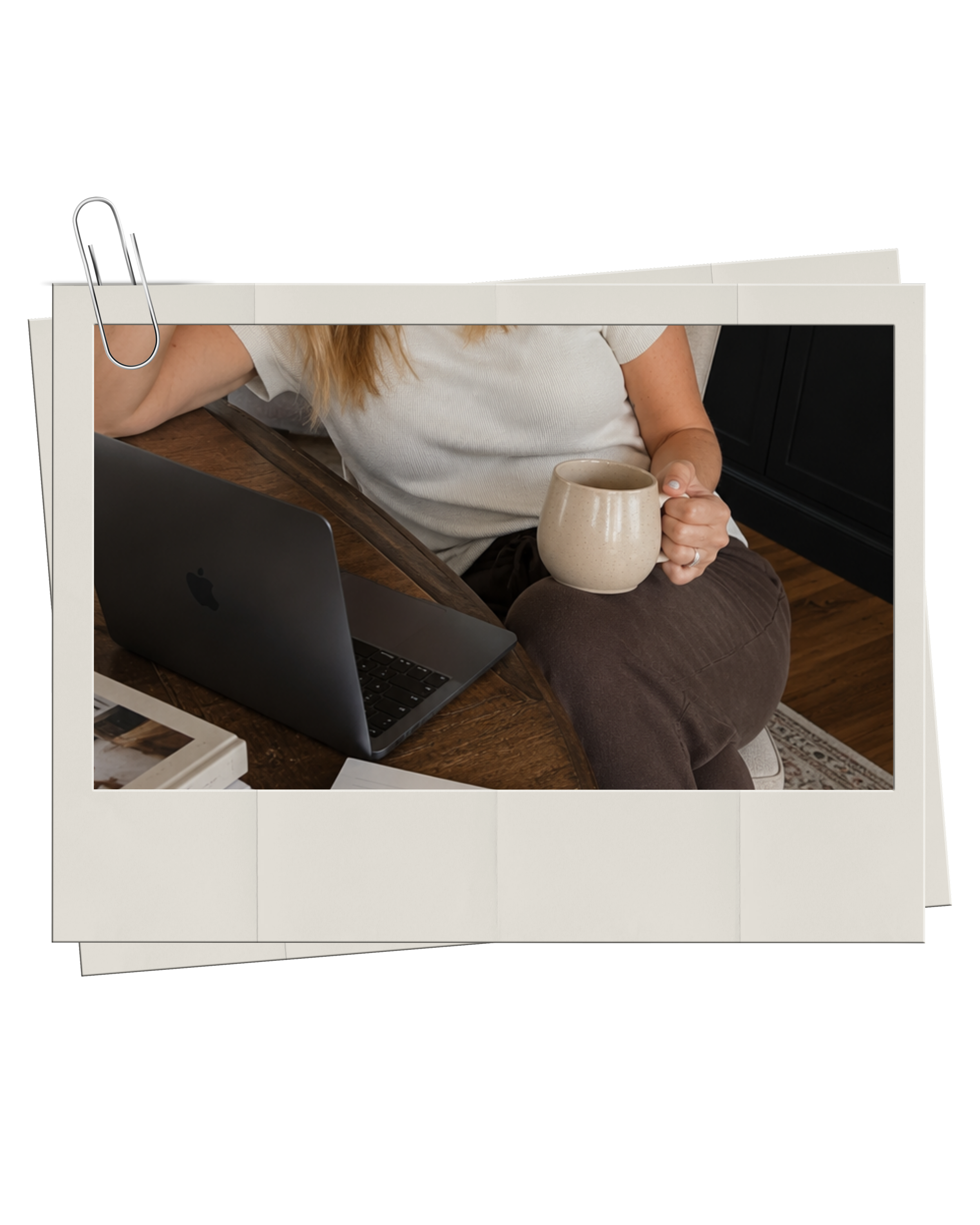 Haus of Whit Brand Photoshoot 2026. Whitney Radacina at a wooden table holding a beige coffee mug. She is wearing a white shirt. A black laptop is open in front of her.