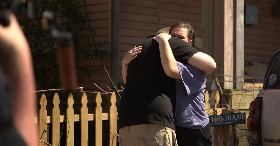 Ryan Hall embraces a community member outside their tornado-damaged home