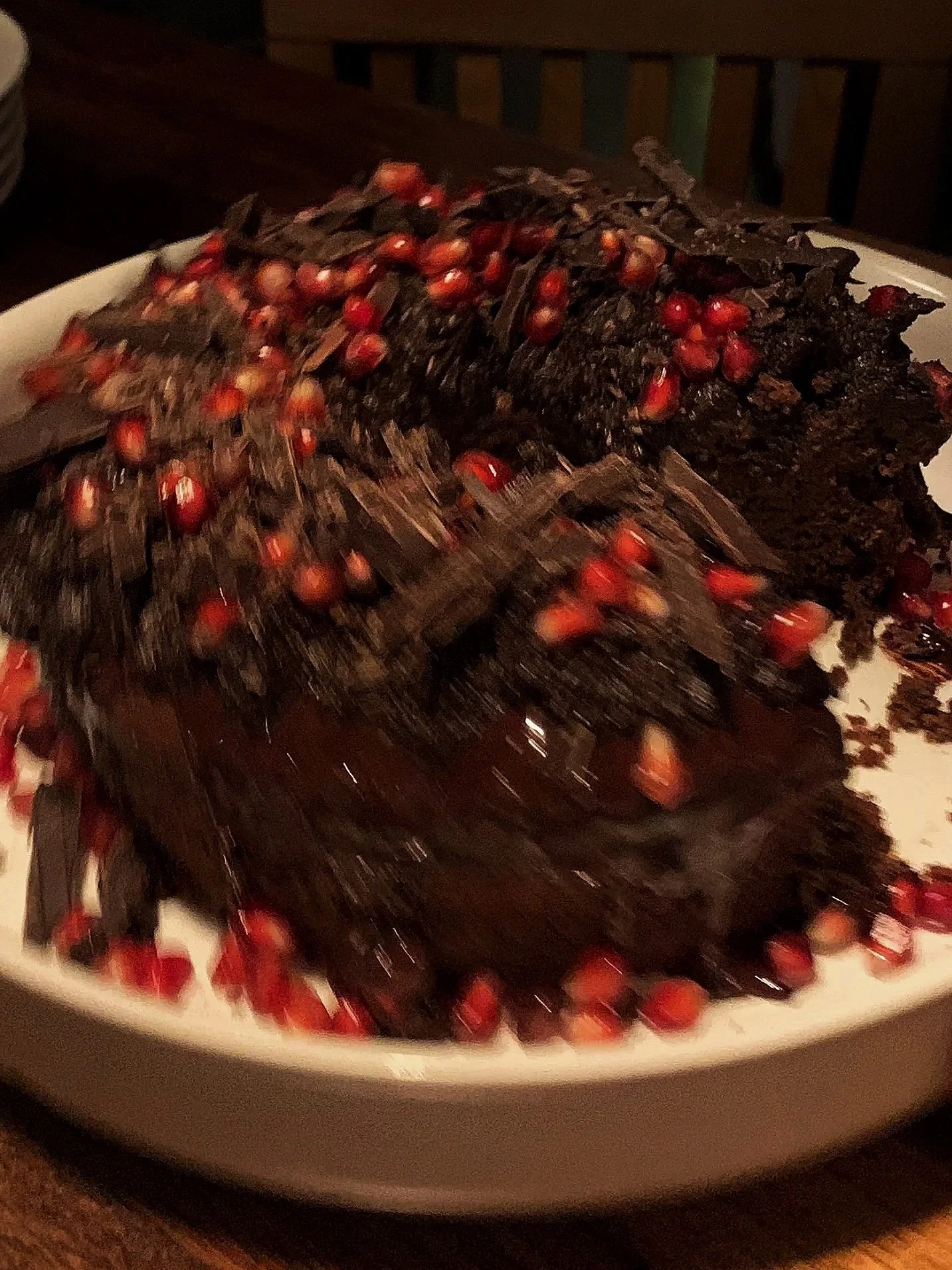Blurred dark chocolate bark cake with pomegranate seeds on a white plate