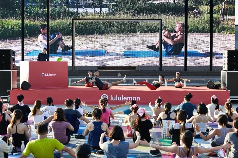 Dean Myers is leading a large group corporate fitness class at a Lululemon-sponsored outdoor event in Seoul